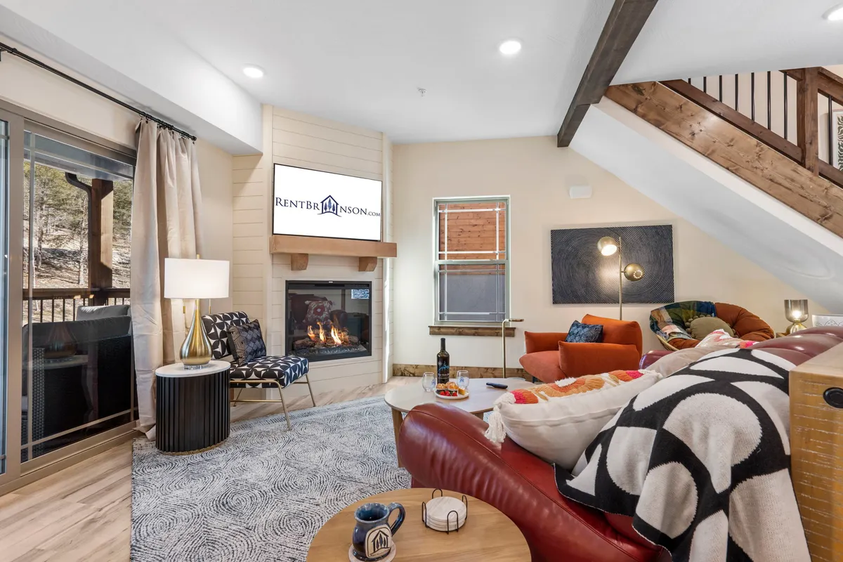 A comfortable living room features a plush sofa, coffee table, a fireplace, and a TV—ideal for both big gatherings and quiet evenings. The ambiance is warm and welcoming, inviting guests to unwind and enjoy each other's company.