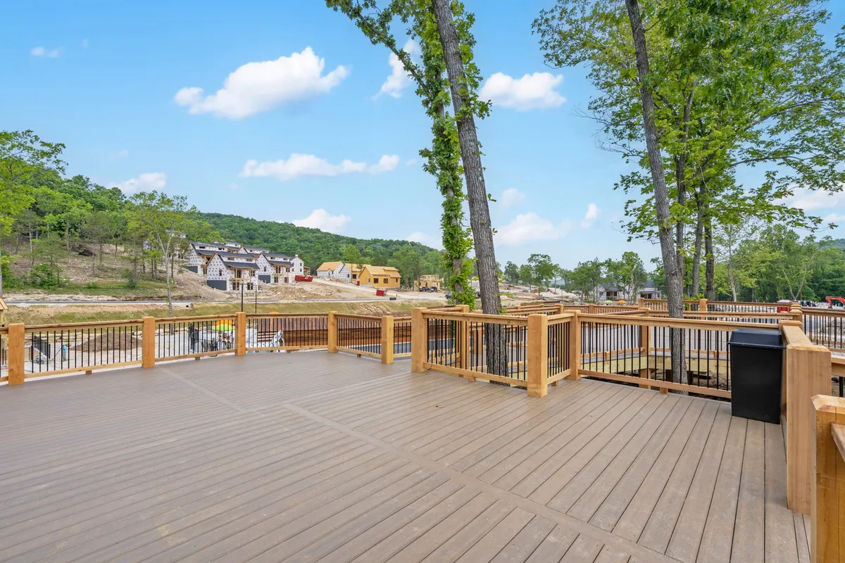 A wooden deck nestled among trees, with comfortable seating and a view of distant houses. This tranquil outdoor space suggests possibilities for morning coffee, barbecues, or simply enjoying the fresh air, with a smooth transition from the home to the outdoors.