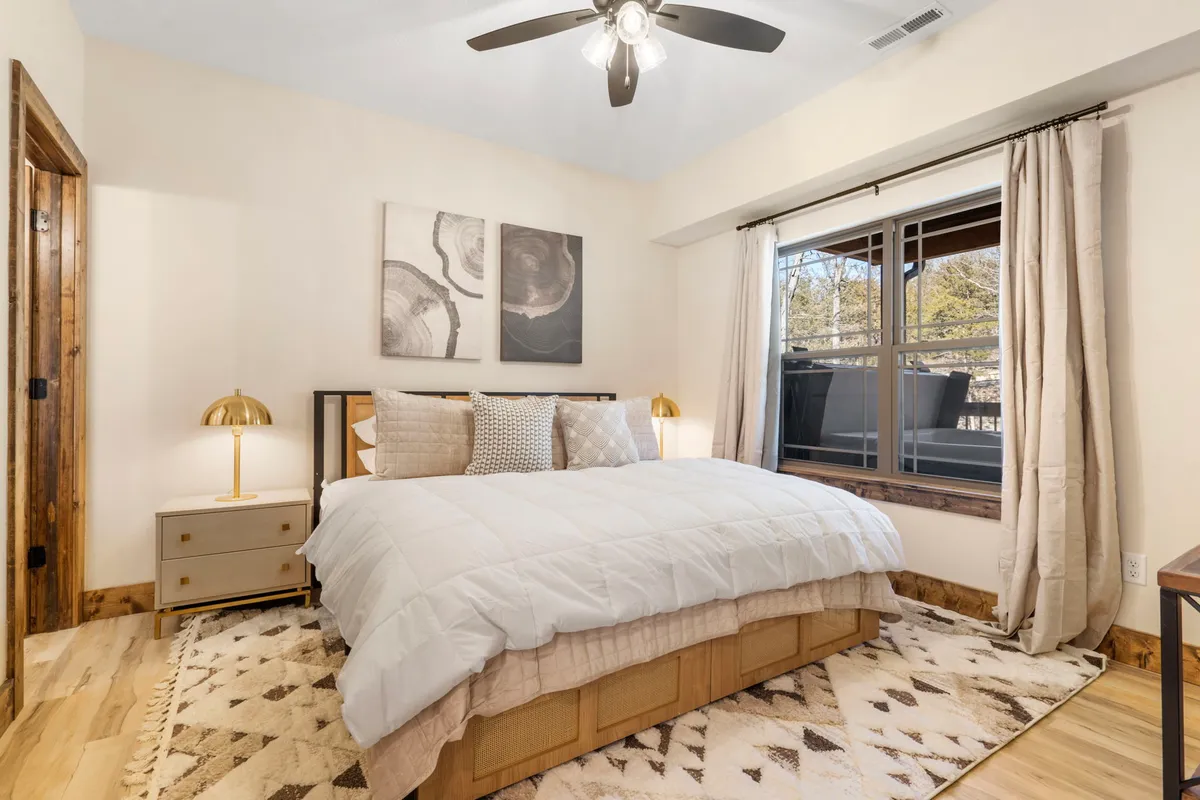 A cozy bedroom with a large bed, a window letting in soft natural light, a bedside lamp, and tasteful artwork on the wall. The plush bedding and neat arrangement create an inviting atmosphere perfect for relaxation.
