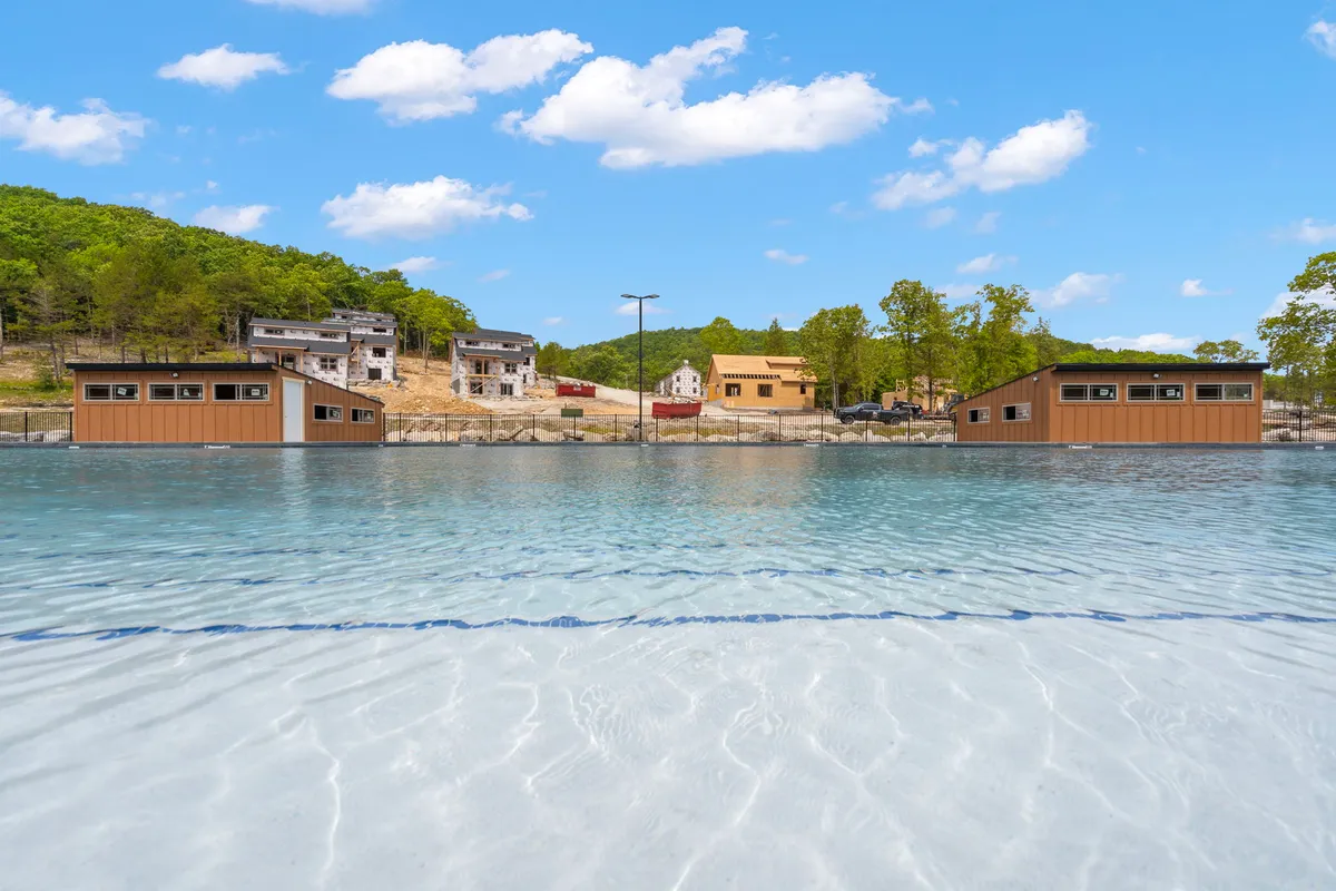 A picturesque lake scene with clear water, tree-lined hills, and houses in the distance. The peaceful setting invites guests to fish, swim, picnic, or simply relax along the shore, emphasizing the area’s natural beauty and opportunities for togetherness.