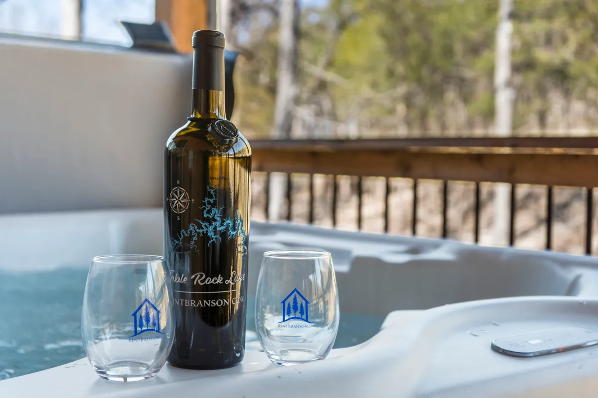 An inviting hot tub is the centerpiece of this scene, accompanied by a wine bottle and two glasses, signaling a space for unwinding and memorable moments with loved ones. The setting is serene, emphasizing relaxation and the enjoyment of the hot tub experience.